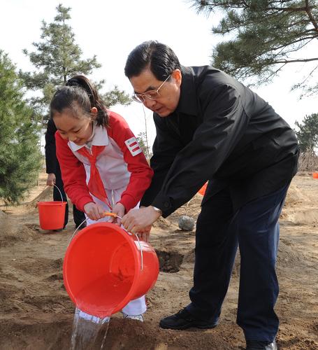 4月2日,党和国家领导人胡锦涛、吴邦国、温家宝、贾庆林、李长春、习近平、李克强、贺国强、周永康来到北京市永定河畔参加首都义务植树活动。这是胡锦涛同少先队员一起给刚栽下的树苗浇水。新华社记者李学仁摄