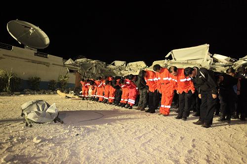 1月16日,在海地太子港,中国国际救援队队员以及公安部、外交部的工作人员在联合国驻海地稳定特派团倒塌大楼现场为挖掘出的一名中方失踪人员默哀。当日,中国国际救援队在海地太子港地震现场挖掘出一具中方失踪人员遗体,并举行了简短的现场默哀仪式。新华社记者 邢广利 摄